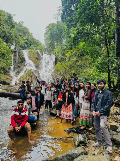 A large group from our Independence Day trip posing in front of a beautiful cascading waterfall, a perfect spot for a group memory.