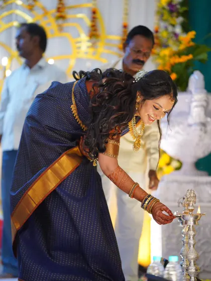 A candid moment of the bride lighting the lamp. Her makeup is subtle yet elegant, designed to look beautiful in every moment of the ceremony.