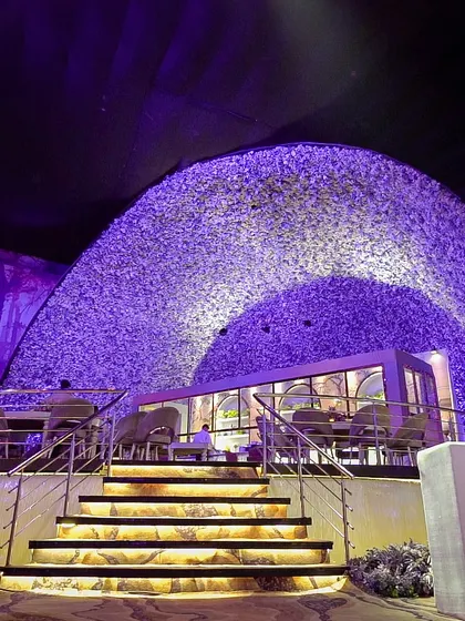 A custom-built food station designed to look like a modern bistro, nestled under a canopy of purple foliage. This is an example of how we can create unique, pop-up restaurant experiences within a larger event.
