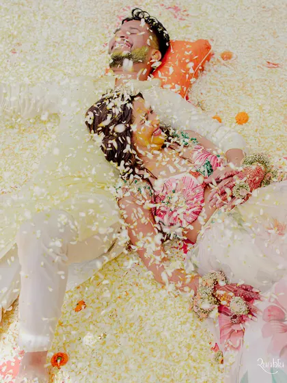 A unique overhead shot of the couple lying down in a sea of flower petals after their haldi, a beautiful and serene end to the chaotic fun.