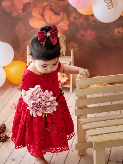 A flower girl in red. This little one looks so sweet and thoughtful, holding a bouquet of pink flowers.