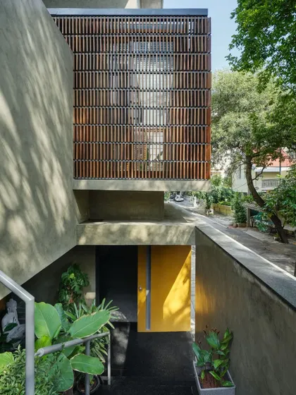 The entrance to 'The Mantle' is a journey through layers, with raw concrete walls and a pop of color leading you into the home.