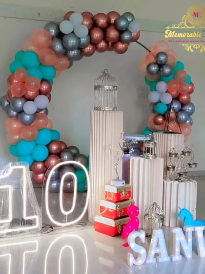 A 10th birthday party setup with a teal, rose gold, and silver balloon ring.