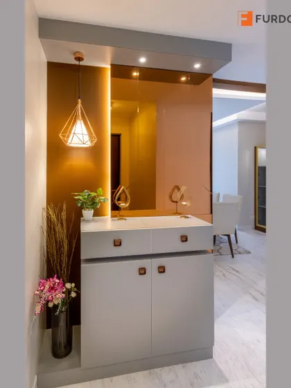 A contemporary foyer design featuring a sleek grey storage cabinet, a large mirror, and a statement geometric pendant light.