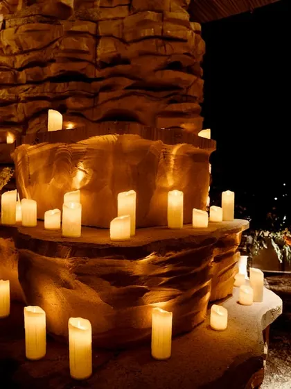 A close-up of the candle-lit rock formations inside the grotto. The warm, flickering light creates an atmosphere of primordial beauty and mystique.