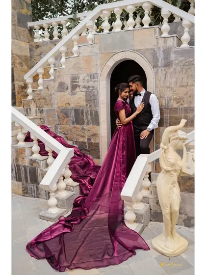 A beautiful couple sharing a moment on a stone staircase, with the bride's long, trailing gown creating a sense of grandeur. This is a perfect example of a classic, romantic pre-wedding shot.
