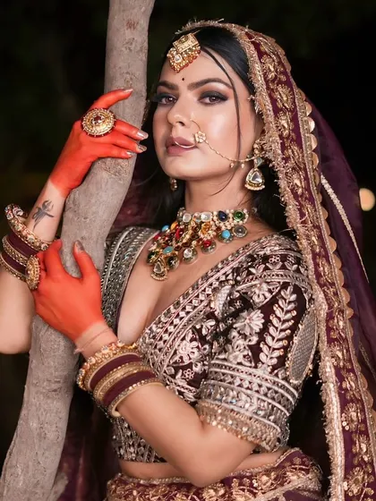 A bride in a deep wine-colored lehenga with heavy silver embroidery, a sophisticated choice for an evening reception.
