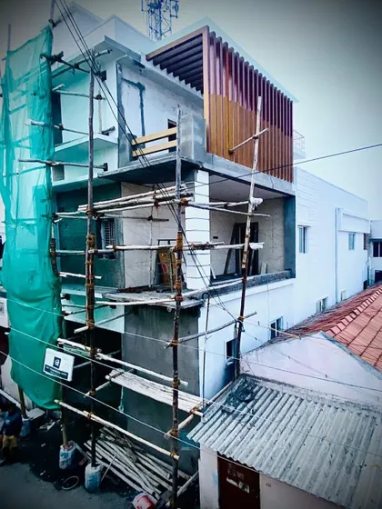 A building facade during the finishing stages of construction. This image shows scaffolding still in place as exterior elements, like the vertical wooden louvers on the upper floor, are being installed.