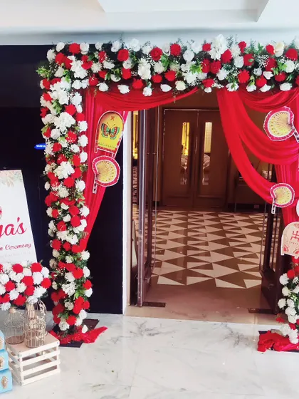 An elegant entrance for a traditional Annaprashan ceremony. I created a beautiful arch with red and white flowers and red fabric drapes, complemented by a welcome sign for the baby's first rice-eating ceremony.