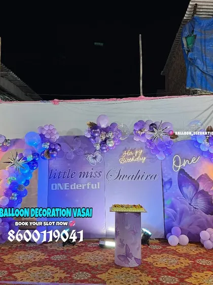 A "Little Miss ONEderful" fairy theme for Swahira's first birthday. This outdoor setup includes a custom purple backdrop, fairy cutouts, and illuminated butterfly wings.
