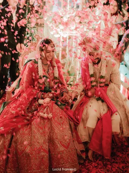 A candid moment of the couple laughing together, covered in a shower of pink petals.