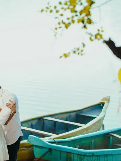 A tender pre-wedding moment by the water, with the groom kissing the bride's forehead.