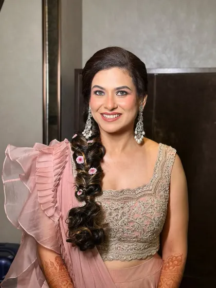 A portrait of pure elegance. This look features a dewy, fresh base, defined eyes, and a soft pink lip, all designed to complement her ruffled saree and radiant smile.