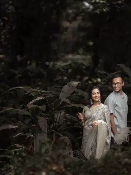 A wide shot of a couple in a forest, giving a sense of scale and the feeling of being surrounded by nature during their pre-wedding shoot.