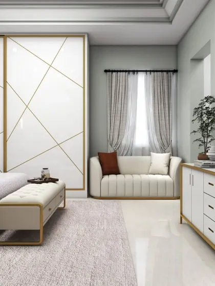 A luxurious master bedroom with a white and gold theme. The design includes a large sliding wardrobe with geometric gold inlays, a matching TV console, and a comfortable sofa, creating a bright and glamorous space.