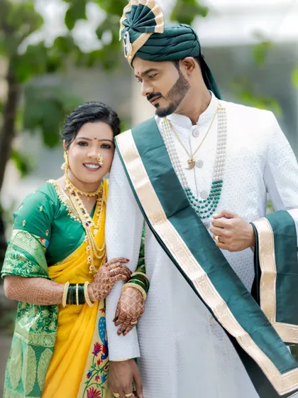 A classic portrait pose, with the bride holding onto the groom's arm, both looking confidently at the camera.