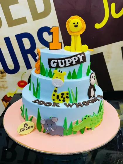 A grand 4kg three-tiered jungle cake for a first birthday, with fondant animals climbing up the sides.