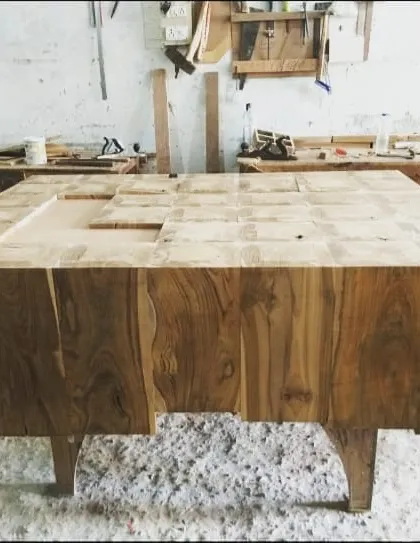 This custom center table, made from blocks of solid teak wood, is seen here mid-process. The varied grain of the wood blocks creates a rich, patchwork-like surface.
