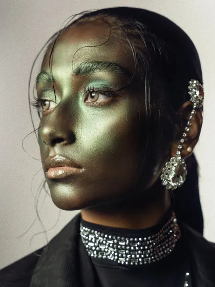 A profile view of the metallic green conceptual makeup, highlighting the model's features and the unique texture of the makeup.