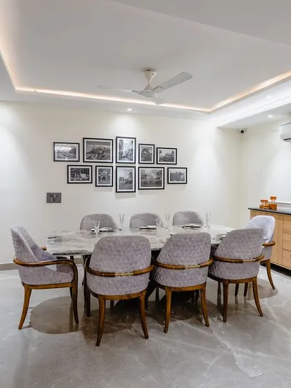 This eight-seater dining hall has a clean, minimalist aesthetic. The grey quilted chairs with gold accents add a touch of luxury to the simple marble table.