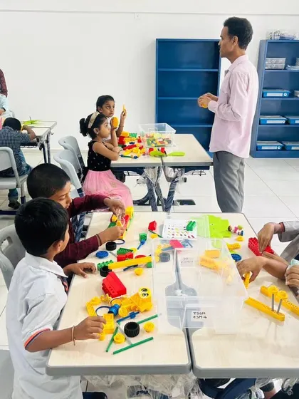 An instructor oversees a bustling classroom at The School for Global Minds, where young students are busy with their LEGO Education kits.