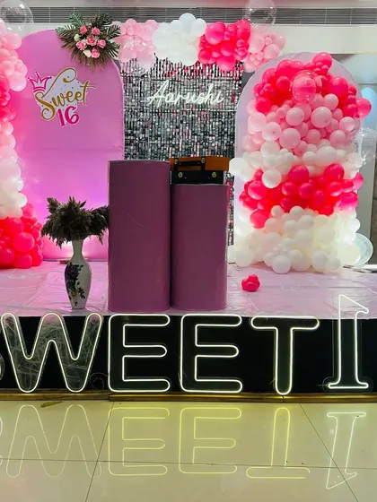 Celebrate a Sweet 16 with this glamorous pink and white decoration. It features a "Sweet 16" neon sign, a silver shimmer wall for photos, and elegant balloon arrangements to create a sophisticated party atmosphere.