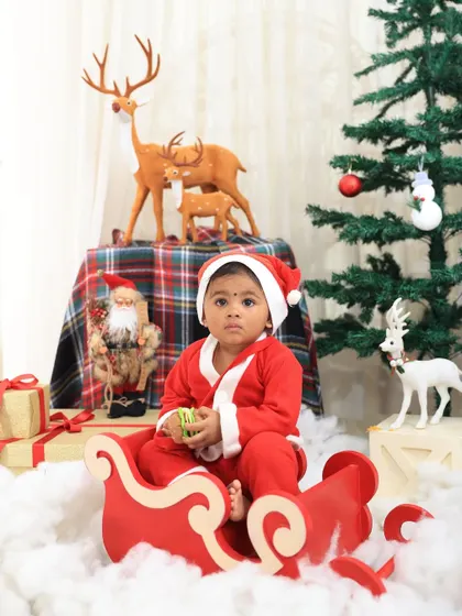 A classic Santa Claus look for a baby's first Christmas. This little one is sitting in a sleigh, creating a timeless holiday photo.