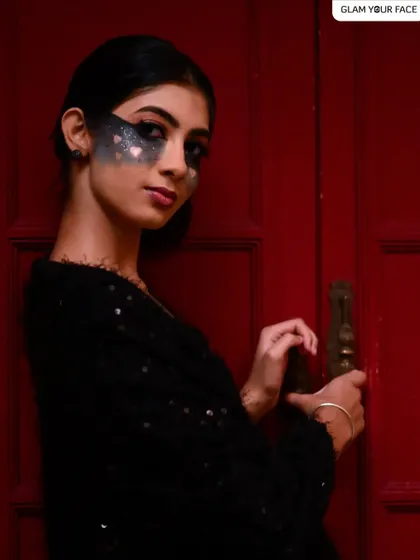 A moody shot from the "Valentween" series. The creative makeup with dark, smoky hearts stands out against the dramatic red background.