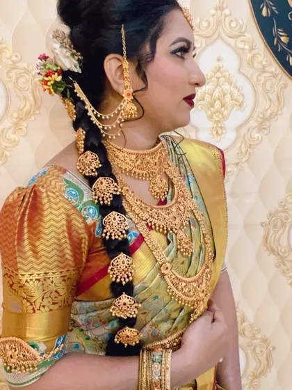 A traditional South Indian bridal hairstyle featuring a long braid decorated with multiple gold `jadanagam` hair ornaments.