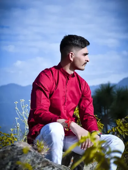 An environmental portrait of the groom sitting on a rock, with the mountains visible in the background. This connects the person to the beautiful Himachali landscape.