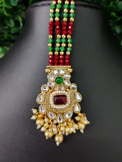 A rectangular maang tikka with kundan work and colorful bead strands. This is a vibrant and unique piece for a festive look.