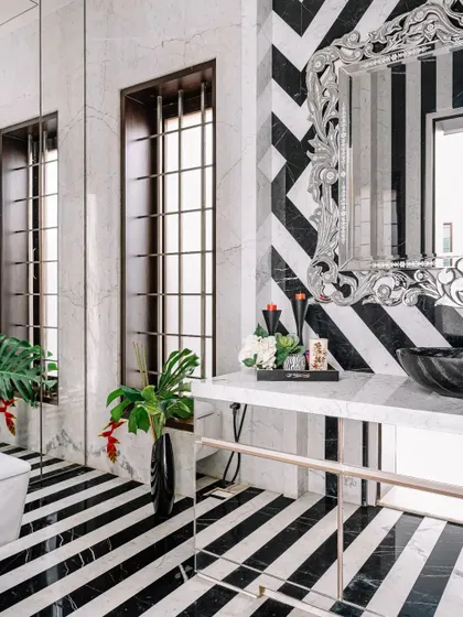 I love to play with bold patterns. In this powder room, we used black and white marble to create a dramatic piano-key striped floor and a chevron-patterned wall. The ornate silver mirror adds a touch of glamour to the graphic design.