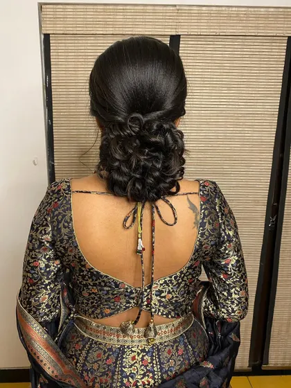 A beautiful messy bun with curled tendrils, a modern and romantic choice for a reception or sangeet.