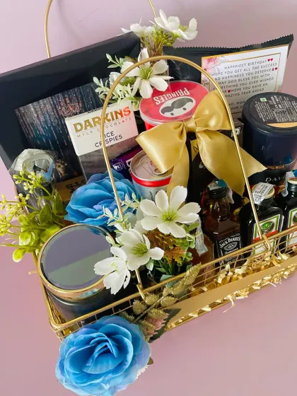 This luxurious metal basket hamper is filled with premium items, including miniature liquor bottles, chocolates, and snacks, all arranged with beautiful blue flowers.
