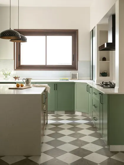 The spacious kitchen is grounded by classic checkerboard flooring in grey and white. A large central island in warm oak provides extra workspace and a place for casual meals.