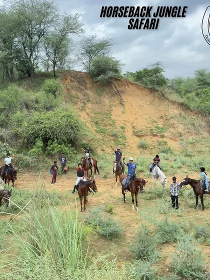 A happy group of riders pauses for a photo against a backdrop of the hilly Aravali terrain. This is a typical scene from our horseback jungle safari, showing the scale and beauty of the landscape.