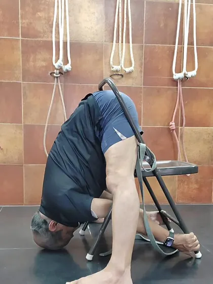 A deep forward bend using a chair for support. This variation of Parsvottanasana allows for a passive release of the spine and hamstrings.