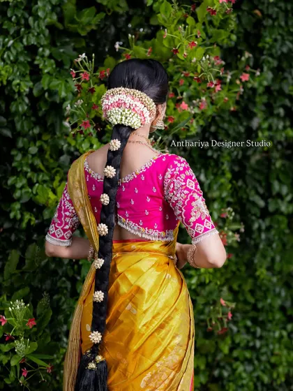 The back view of the model, showing her traditional braided hairstyle and the detailed blouse back.