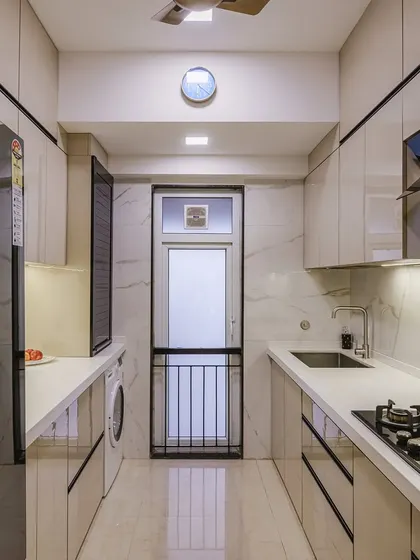 This parallel kitchen layout in beige and black offers a sleek, modern aesthetic. The glossy finish on the cabinets reflects light, making the space feel brighter and more open.