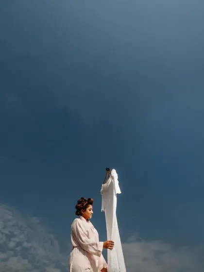 A low-angle shot of the bride with her dress against the sky, creating a powerful and minimalist composition.