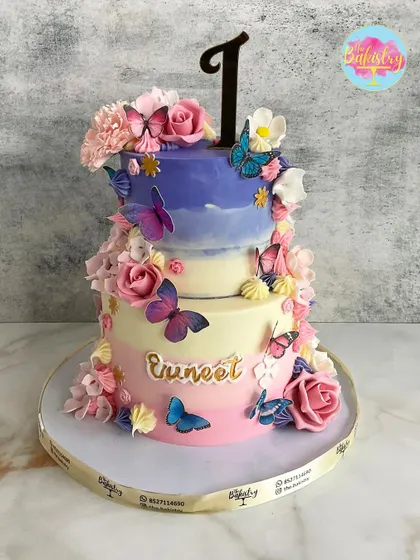 A stunning two-tiered butterfly and floral cake for Evneet's first birthday. The ombre colors and delicate, fluttering butterflies create a beautiful garden effect.