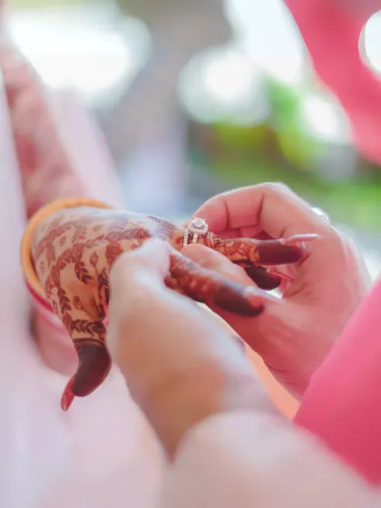 A detailed shot of the ring exchange, a pivotal moment in any engagement or wedding ceremony. The focus on the hands and the ring tells a story of commitment.