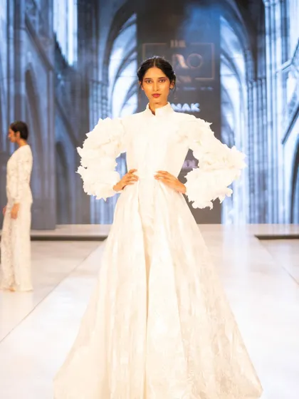 This dramatic all-white gown at The Luxo Show was paired with a bold red lip and a sleek, braided hairstyle. This look shows how a pop of color can create a memorable and high-fashion bridal statement.