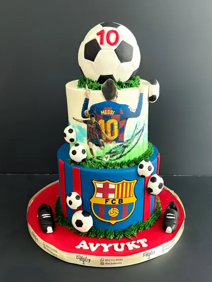 A straight-on shot of the epic two-tiered Messi and FCB-themed football cake, perfect for any soccer enthusiast.