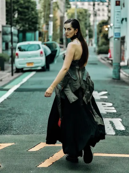 A walking shot on a quiet Tokyo street. The over-the-shoulder glance creates a sense of narrative, as if the viewer has just caught a fleeting moment.