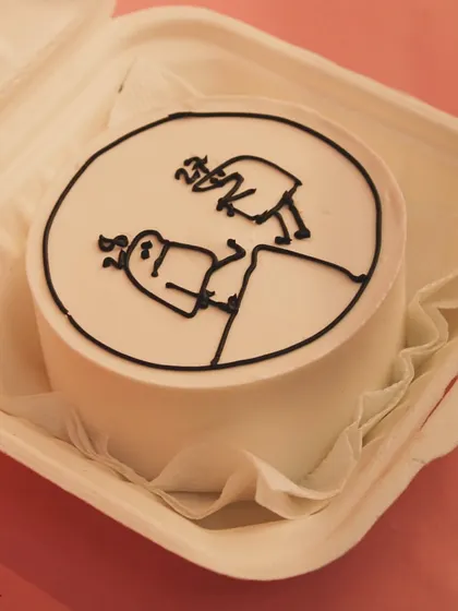 A fun and quirky bento cake with a minimalist cartoon design, showcasing our ability to create custom and playful artwork on our mini cakes.