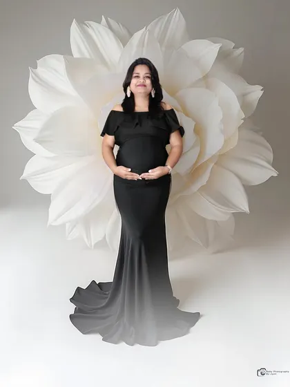 A chic and modern solo portrait in a sleek black gown. The oversized white paper flower in the background provides a beautiful and artistic contrast.