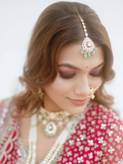 A close-up on the bride's makeup for her pheras. The focus is on her flawless skin and the deep red eyeshadow that complements her traditional red and green lehenga.