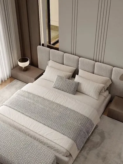 An overhead view of a bedroom with a textured grey bed and bench. The wooden floor and large windows create a warm and inviting space.