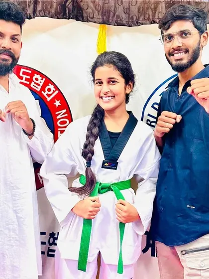 A student smiles after receiving her green belt.